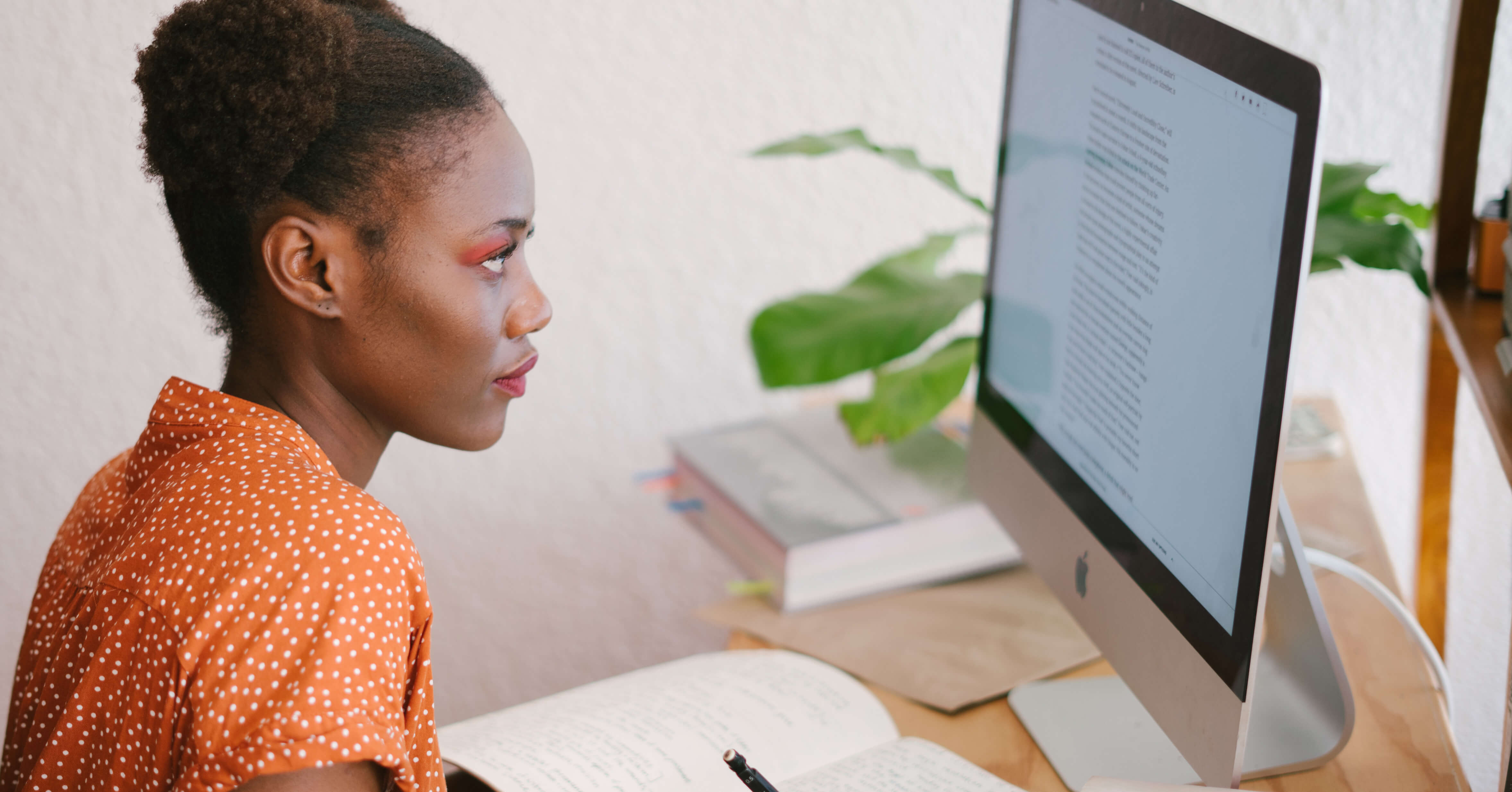 Woman Reading a Computer Screen and Taking Notes