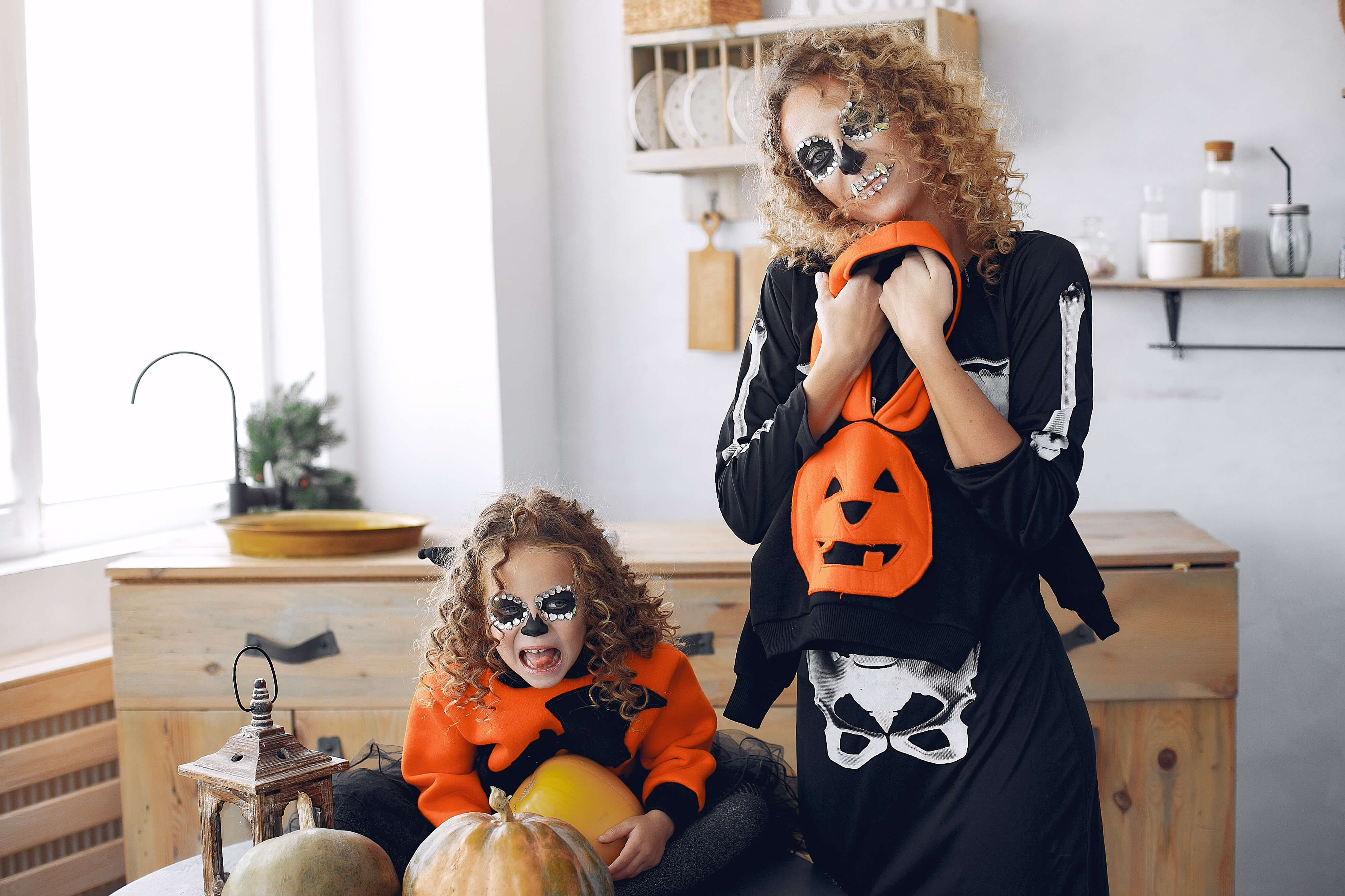 Halloween. Mother and daughter in halloween costumes. Family at home with pumpkins.